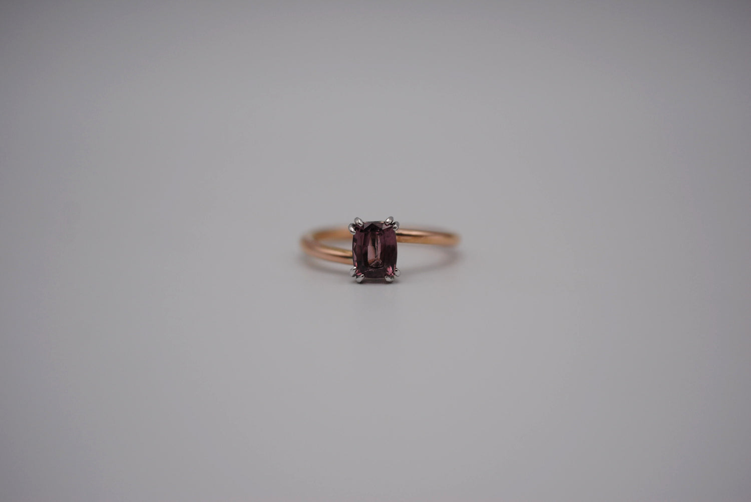 An emerald cut Malaia Garnet ring with a rose gold band and white gold setting. 