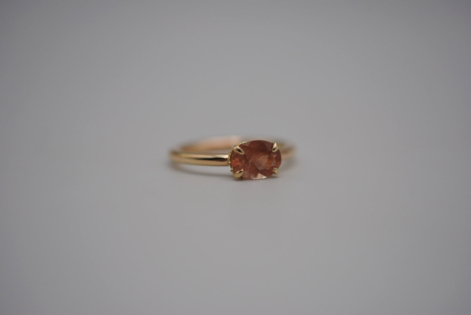 Oval cut Oregon Sunstone ring on a yellow gold band. 